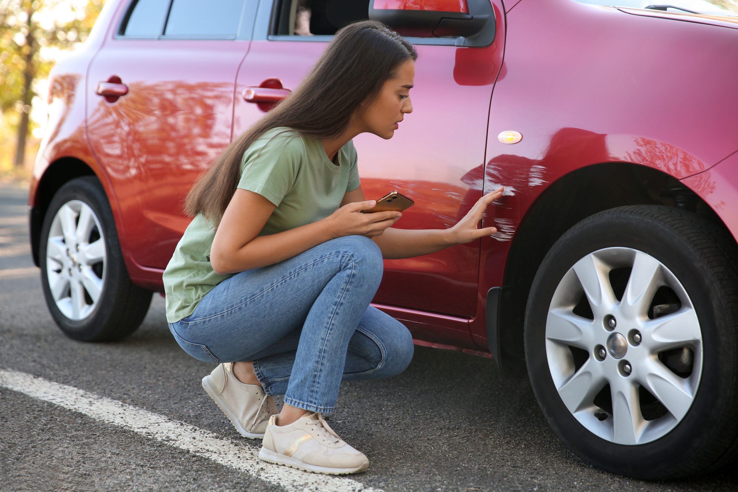 Woman assessing car damage for insurance